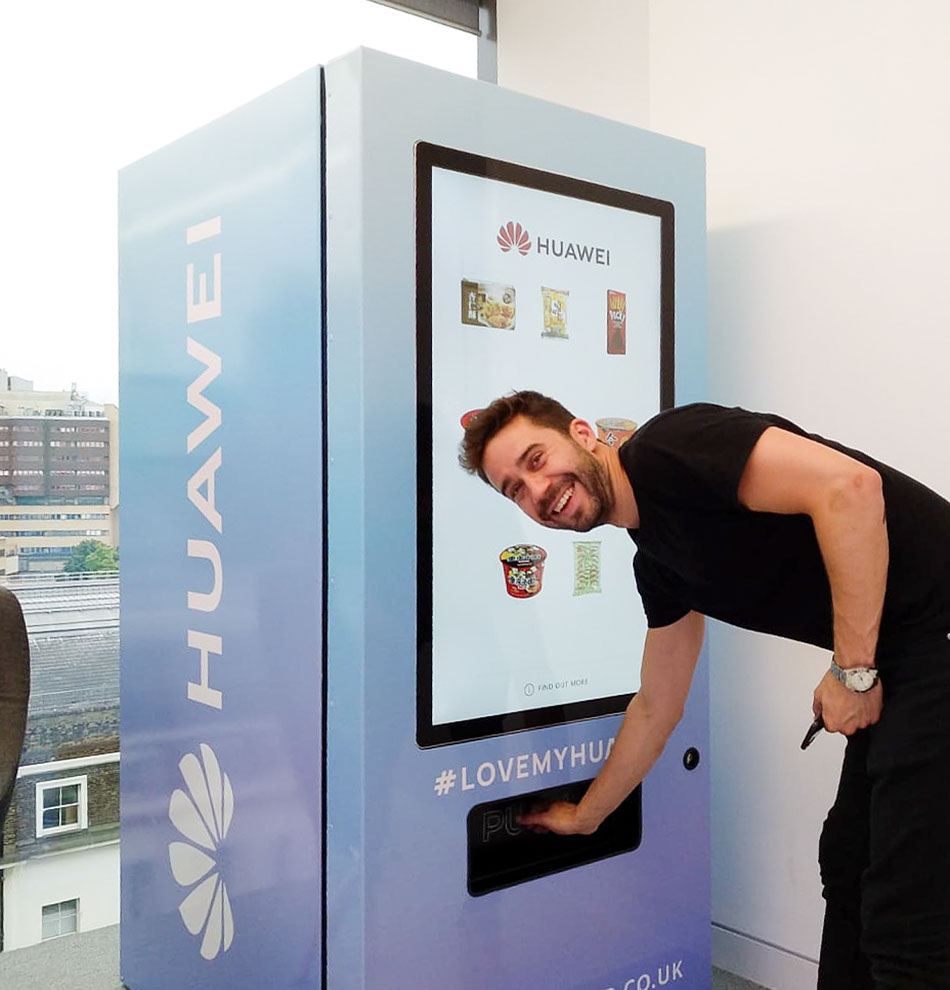 Man smiling at camera and getting his purchase out of a vending machone